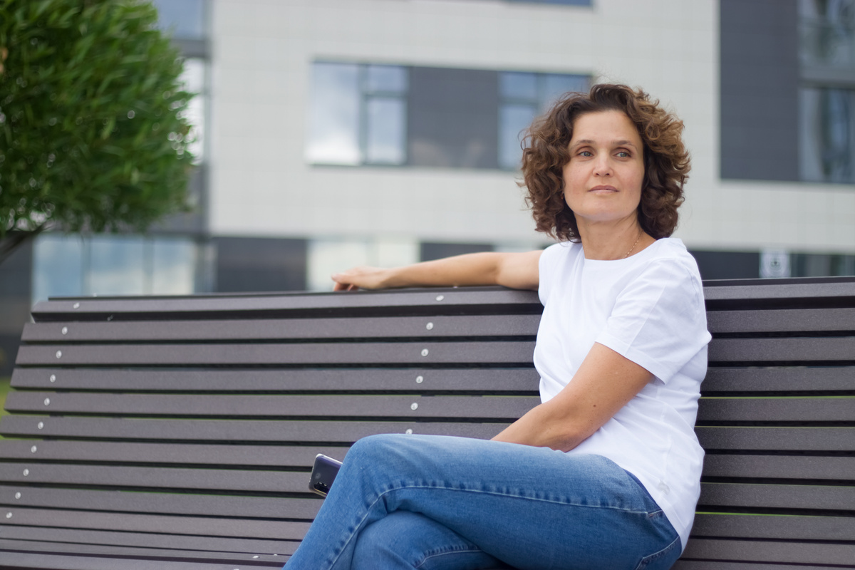 A 45-50 years old woman is sitting on a bench.